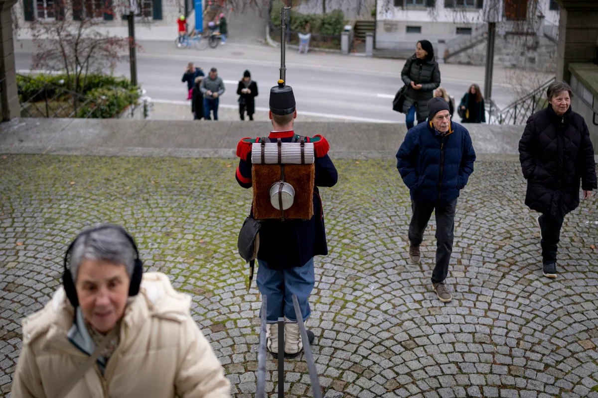 … strömten die Gäste eilig ins Innere der reformierten Kirche Uster. Man sieht Besucher zur Kirche laufen, vorbei an einem Soldaten, der Ehrenwache hält.